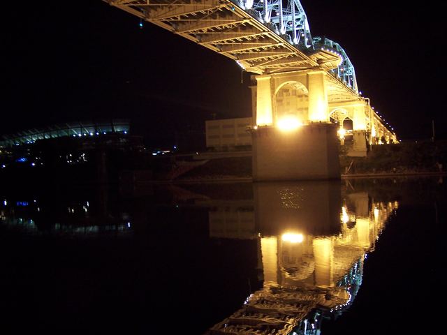 A lit bridge at night, reflected in the water